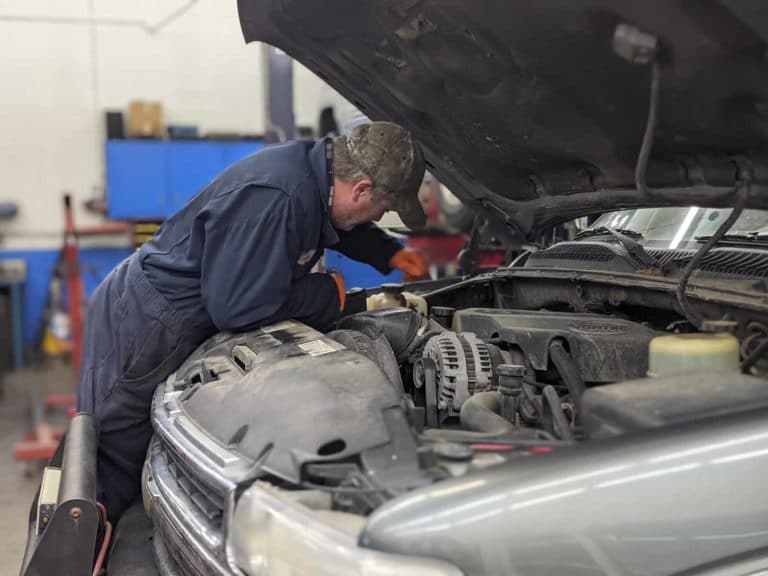 Technician inspecting engine compartment of vehicle. Brandy's Automotive. Bend, Oregon. Truck and car repair.